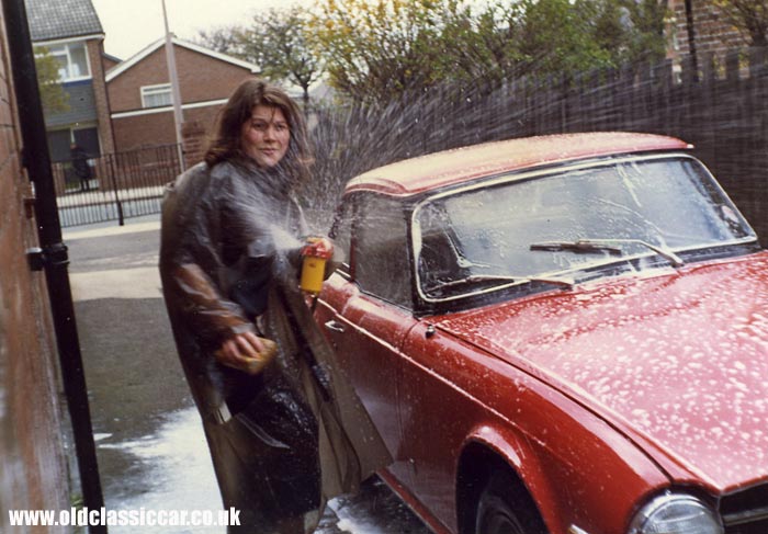 Red Triumph sportscar being washed in the 1970s